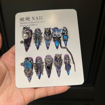 Handmade Blue Purple Cat Eye Long Stiletto Press On Nails. Dark gothic false nails decorated with 3D silver skull, butterfly & cross charms, heart gems, pearls and dangling metal chains. Reusable fake nails for parties, cosplay and Halloween.