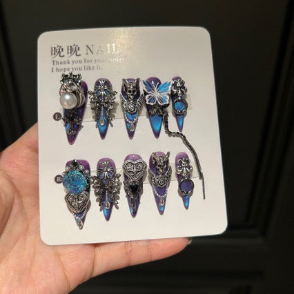 Handmade Blue Purple Cat Eye Long Stiletto Press On Nails. Dark gothic false nails decorated with 3D silver skull, butterfly & cross charms, heart gems, pearls and dangling metal chains. Reusable fake nails for parties, cosplay and Halloween.