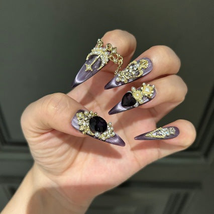 Handmade Purple Cat Eye Long Coffin Press On Nails. Dark royal gothic false nails decorated with large black heart & oval gems, vintage gold crown and cross charms, pearls, gold rhinestones and dangling gold chains