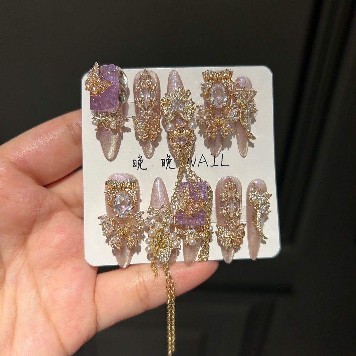 Champagne Pink & Purple Cat Eye Stiletto Press-on Nails with Purple Crystal Gem, Gold Rhinestone Bow, and Interlinked Hanging Chain - Luxury Glam Fake Nail Set