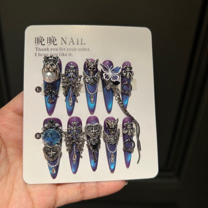 Handmade Blue Purple Cat Eye Long Stiletto Press On Nails. Dark gothic false nails decorated with 3D silver skull, butterfly & cross charms, heart gems, pearls and dangling metal chains. Reusable fake nails for parties, cosplay and Halloween.