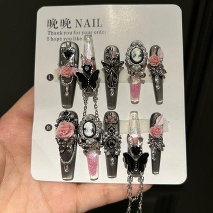 Handmade Metallic Silver Long Stiletto Press On Nails. Vintage gothic coquette false nails decorated with 3D pink roses, portrait cameo, black butterfly, pearls, silver rhinestones and dangling silver chains. Reusable fake nails for parties and cosplay.