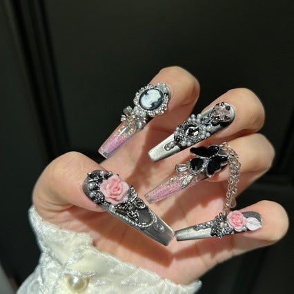 Handmade Metallic Silver Long Stiletto Press On Nails. Vintage gothic coquette false nails decorated with 3D pink roses, portrait cameo, black butterfly, pearls, silver rhinestones and dangling silver chains. Reusable fake nails for parties and cosplay.