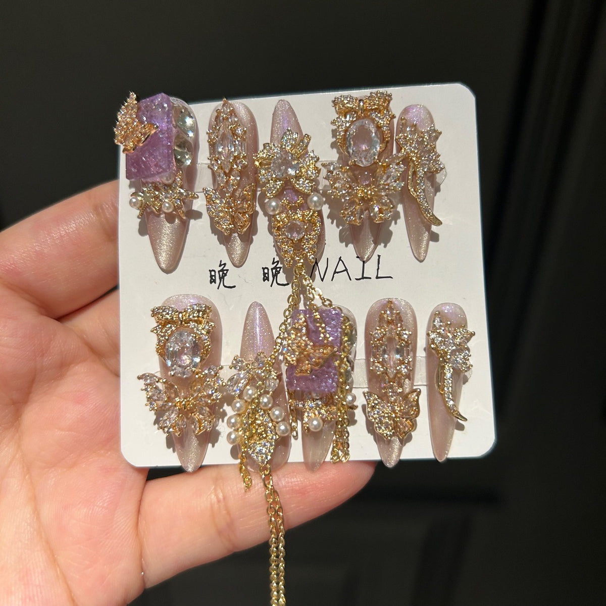 Champagne Pink & Purple Cat Eye Stiletto Press-on Nails with Purple Crystal Gem, Gold Rhinestone Bow, and Interlinked Hanging Chain - Luxury Glam Fake Nail Set