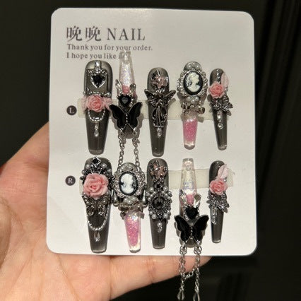 Handmade Metallic Silver Long Stiletto Press On Nails. Vintage gothic coquette false nails decorated with 3D pink roses, portrait cameo, black butterfly, pearls, silver rhinestones and dangling silver chains. Reusable fake nails for parties and cosplay.