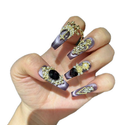 Handmade Purple Cat Eye Long Coffin Press On Nails. Dark royal gothic false nails decorated with large black heart & oval gems, vintage gold crown and cross charms, pearls, gold rhinestones and dangling gold chains