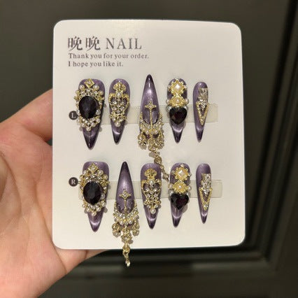 Handmade Purple Cat Eye Long Coffin Press On Nails. Dark royal gothic false nails decorated with large black heart & oval gems, vintage gold crown and cross charms, pearls, gold rhinestones and dangling gold chains