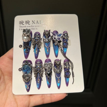 Handmade Blue Purple Cat Eye Long Stiletto Press On Nails. Dark gothic false nails decorated with 3D silver skull, butterfly & cross charms, heart gems, pearls and dangling metal chains. Reusable fake nails for parties, cosplay and Halloween.