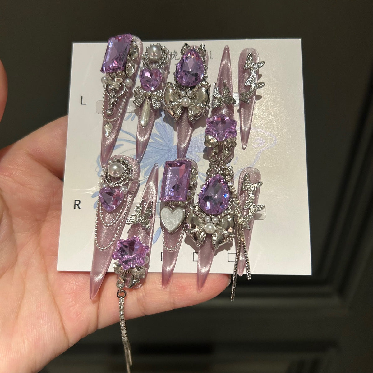 Handmade Milky Pink Metallic Long Stiletto Press On Nails with Large Purple Crystals, Rhinestone Bows, Butterfly Charms, Pearls & Dangling Chains
